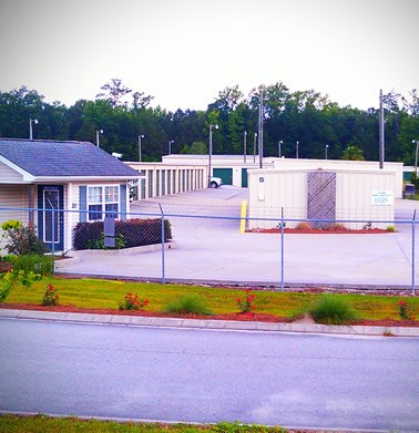 A Smiling Woman Stands In Front Of A Self Storage Facility